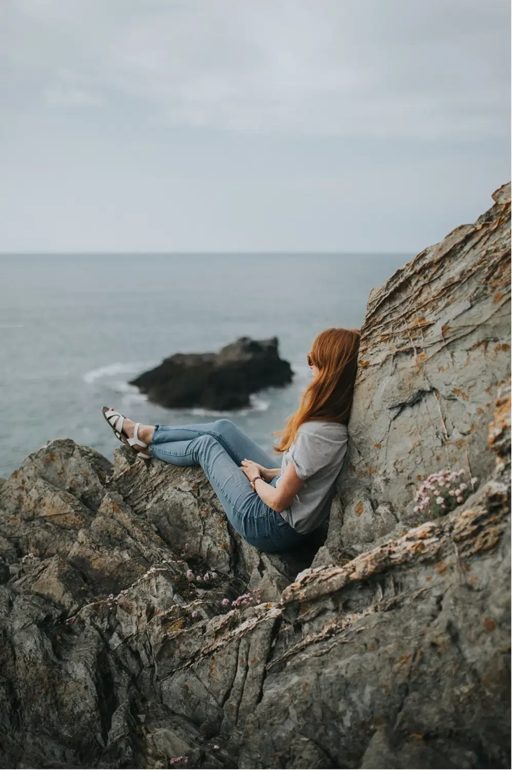 Woman sitting in a rock near ocean